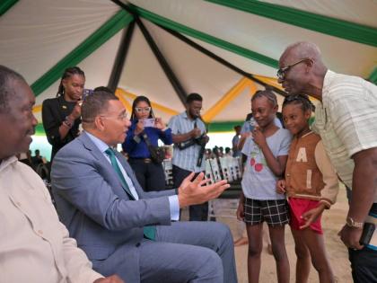 Prime Minister Dr Andrew Holness (second left), greets young Tivoli Gardens residents Cathalia Collins (centre) and Mourica Rose, during the Certificate of Possession Handover Ceremony held at the Tivoli Gardens Community Centre in Western Kingston on Wedn