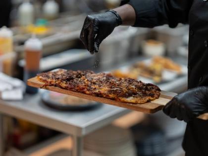 A chef garnishes the cowboy couture BBQ beef flatbread.