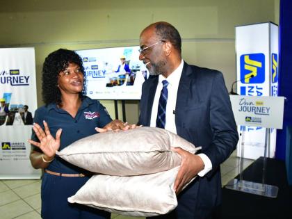 Denise Wheatle (left), operator of Creative Little Kerry House of Fashion and a client of JN Bank Small Business Loans, gifted Earl Jarrett, chief executive officer, The JN Group, a pair of cushions she made. The occasion was a JN members meeting held at t