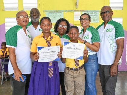 Members of the Morant Bay High School Alumni Association (MBHSAA) and Principal of Easington Primary School, Marigold Webber-Smith (centre), share a photo opportunity with the Top Girl and Top Boy, Jaysianna Hutchinson (third left) and Javien Robb (right),