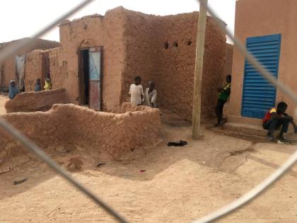 In this photo taken Sunday, April 15, 2018, children look on from behind a wire fence that separates their town from the current airport, in Agadez, Niger.
