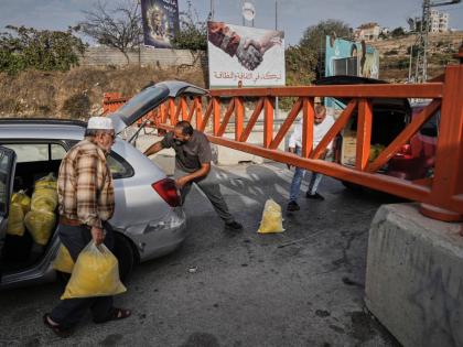 Palestinians transport bags of semolina past a military gate closed to vehicles during an Israeli army operation in Hebron, in the occupied West Bank.