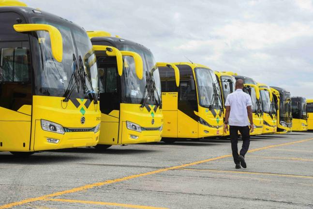 A man walks by a line of JUTC buses at the JUTC Portmore Depot.