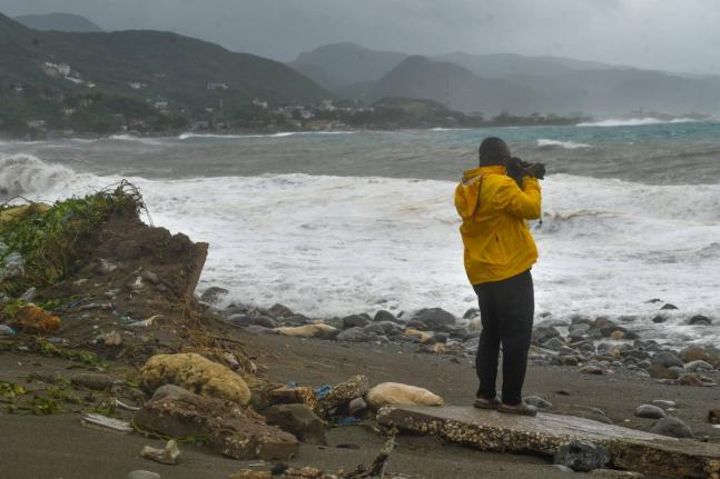 A man takes photographs of the rising waves at Caribbean Terrace in Kingston, as Hurricane Melissa approaches Jamaica.