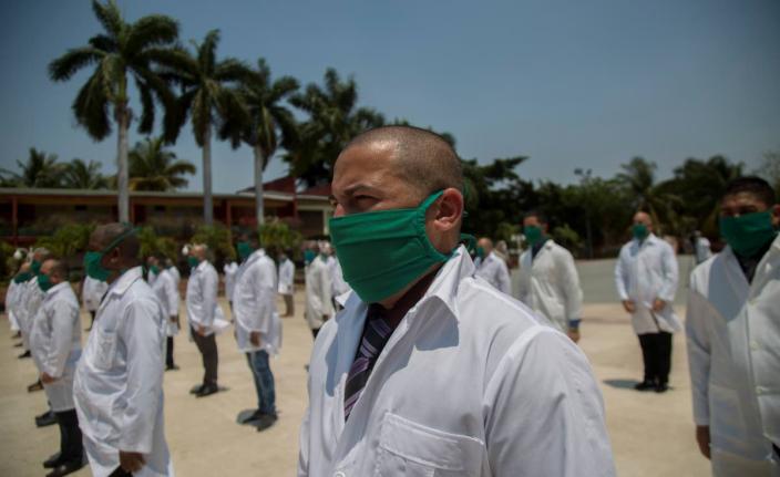 In this 2020 photo doctors form up during a farewell ceremony as they get ready to leave for Italy to help with the new coronavirus pandemic, in Havana, Cuba.