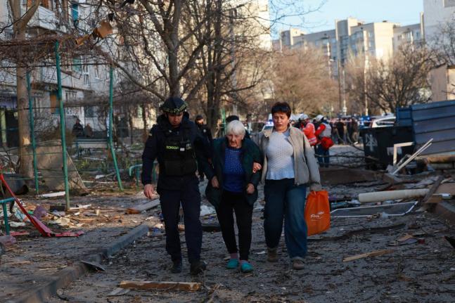 A rescuer helps an elderly woman to leave her home damaged by Russian aerial guided bomb in Zaporizhzhia, Ukraine.