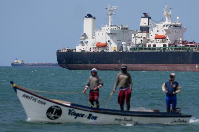 Fishermen pass an oil tanker in the Gulf of Venezuela off the shore of Punta Cardon, Venezuela, January 14, 2026. (AP Photo)