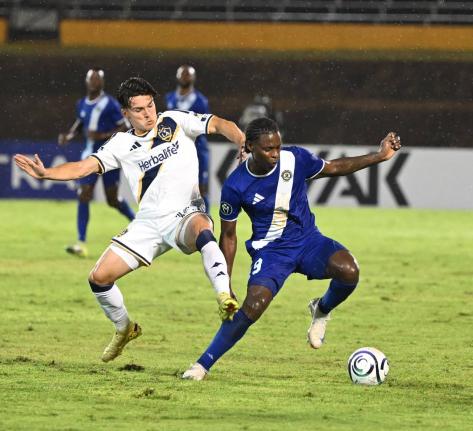 L.A. Galaxy’s Isaiah Parente (left) challenges Mount Pleasant’s Warner Brown during last night’s Concacaf Champions Cup at the National Stadium. LA Galaxy won 3-0.
