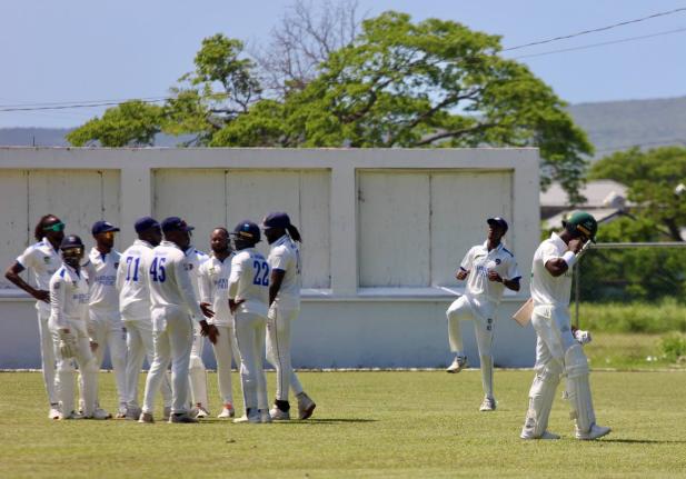 A dejected Romaine Morris (right) leaves the field after being dismissed by Jomel Warrican as the Barbados Pride celebrate on day three of their West Indies Championship game at Chedwin Park yesterday.