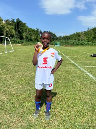 10-year-old Ricshi Scarlett proudly displays her first-place medal at the Scotia Kids Football Championships finals on May 31. The Rousseau Primary student discovered a passion for football after taking up the sport less than a year ago.
