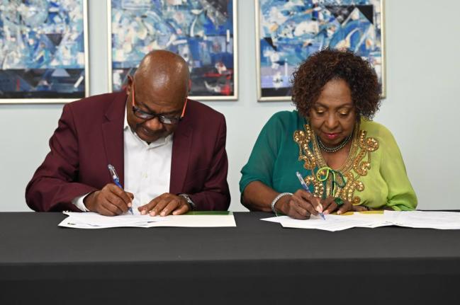 Minister of Culture, Gender, Entertainment and Sport, Olivia Grange (right), and Jamaica Football Federation President Michael Ricketts sign documents committing Jamaica to being one of four hosts of the 2031 FIFA Women’s World Cup at the ministry’s Tr