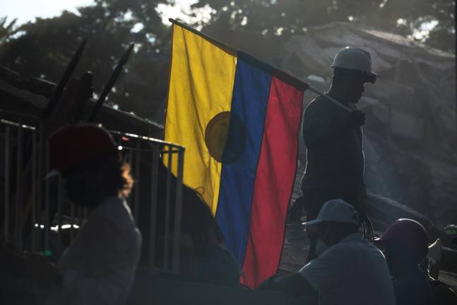 A firefighter working on rescue efforts holds a Colombian flag amid the rubble three days after an earthquake struck Cali, Colombia, August 13.