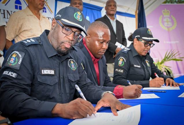 President of the St John Heights Neighbourhood Watch, Yian Shettlewood (centre), signs the memorandum of understanding with Assistant Commissioner of Police in charge of the Community Safety and Security Branch, Charmaine Shand (right); and Senior Superint