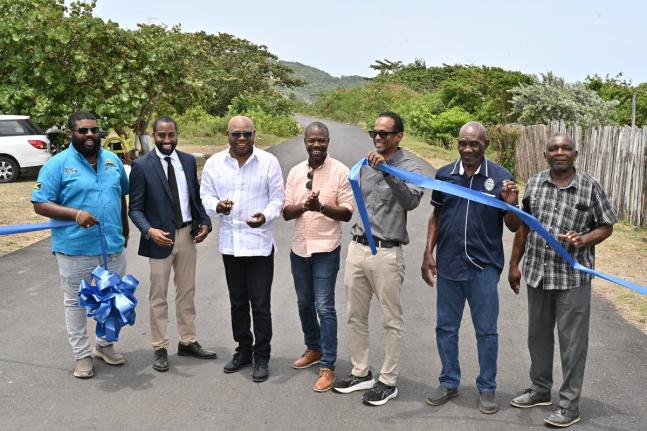 Minister of Tourism, Edmund Bartlett (third left) cuts the ribbon to officially open the rehabilitated roadway between Robins Bay and Strawberry Fields, St Mary, on Wednesday. Sharing in the moment are (from left) Mark Knight, managing director, Wadmar Con