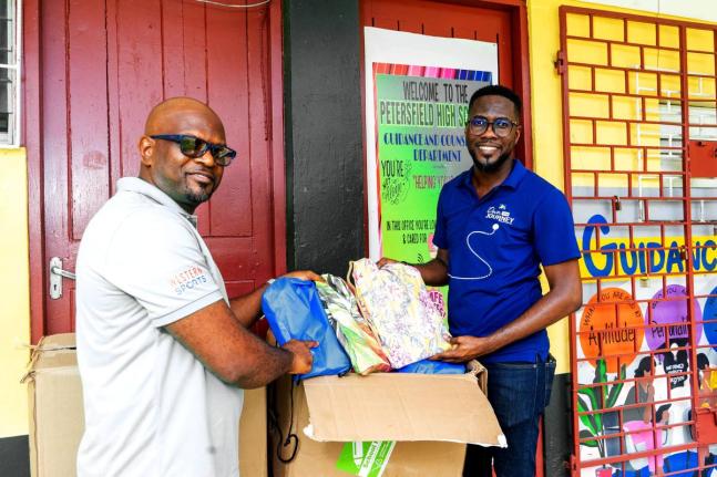 Omar Wright (right), lead, Environment and Community Development at the JN Foundation, hands over back-to-school-supplies to Roan Green, principal of Petersfield High School in Westmoreland. JN Foundation made the donation to the institution during a visit