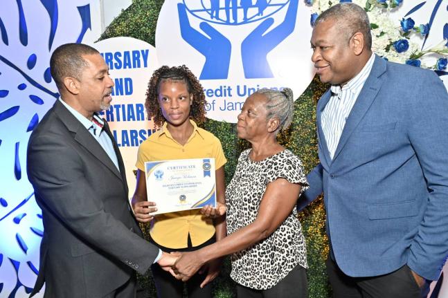 Robin Levy (left), CEO of the Jamaica Co-operative Credit Union League (JCCUL), and Lebert Langley (right), Property Services Manager at JCCUL, chat with scholar Janoya Robinson and her mother, Deleen Brown, after presenting Janoya with the Milburn Corrie 