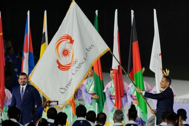 President of the Olympic Council of Asia, Sheikh Joaan Bin Hamad Al Thani (left) looks at the Olympic Council of Asia flag as Sheikh Mohammed bin Abdulrahman Al Thani, Prime Minister of Qatar holds it during the closing ceremony for the Asian Games in Nago