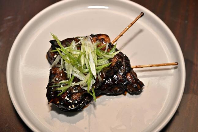 Sesame chicken skewers are marinated in sesame oil and house seasoning, seared and smothered in the house sesame charcoal sauce.