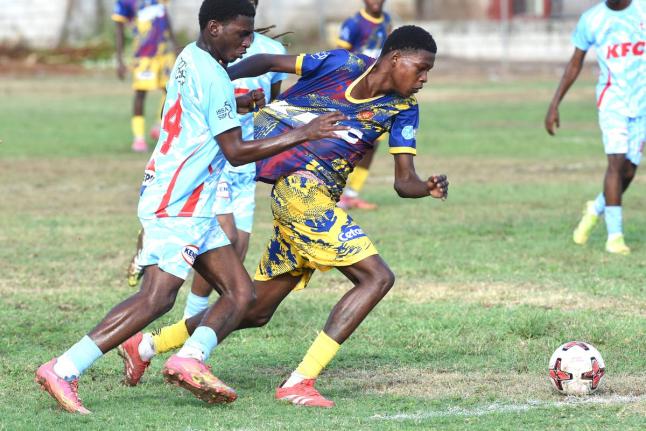 St Andrew Technical High School’s Marvin Henry (right) tries to get away from the very close attentions of St George’s College’s Roshawn Barnett during their Manning Cup football match played at Bumper Hall yesterday.
