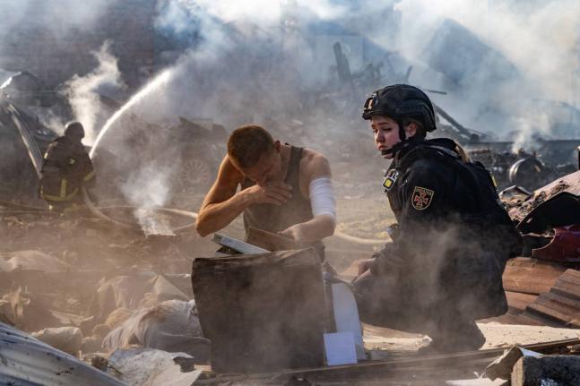 An injured man collects his personal belongings in front of his house destroyed in a Russian strike on Kharkiv, Ukraine, Sunday.