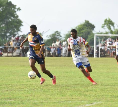 Munro College’s Aston Jones-Williams (left) dribbles ahead of chasing St Elizabeth Technical High player Shavarie Walker during their ISSA daCosta Cup second-round football match at Munro yesterday.