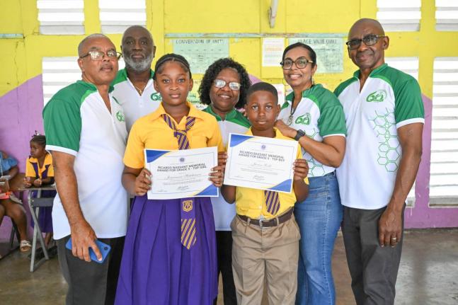 Members of the Morant Bay High School Alumni Association (MBHSAA) and Principal of Easington Primary School, Marigold Webber-Smith (centre), share a photo opportunity with the Top Girl and Top Boy, Jaysianna Hutchinson (third left) and Javien Robb (right),