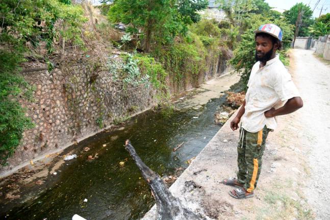 Sadekie Reid stands on the banks of Cassava Piece Gully where his grandmother Sonia Dubar fell and sustained injuries.