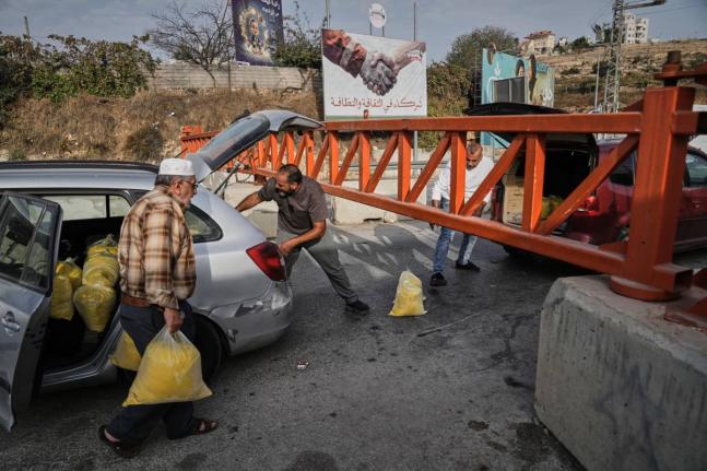 Palestinians transport bags of semolina past a military gate closed to vehicles during an Israeli army operation in Hebron, in the occupied West Bank.