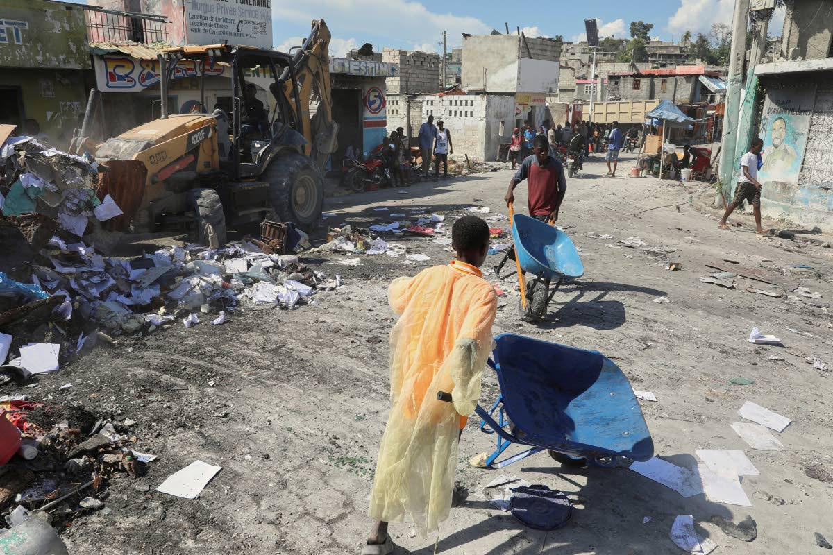 Youths use wheelbarrows to carry debris out of their homes, which were damaged by gang violence, in the Solino neighbourhood of Port-au-Prince, Haiti, Wednesday, September 10, 2025. (AP Photo/Odelyn Joseph)