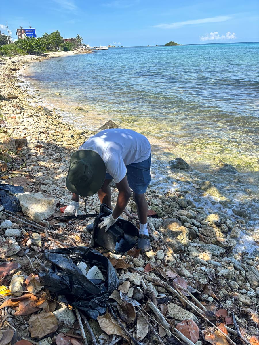 A volunteer places plastic waste into a garbage bag during the beach clean-up organised by Fi We Children Foundation