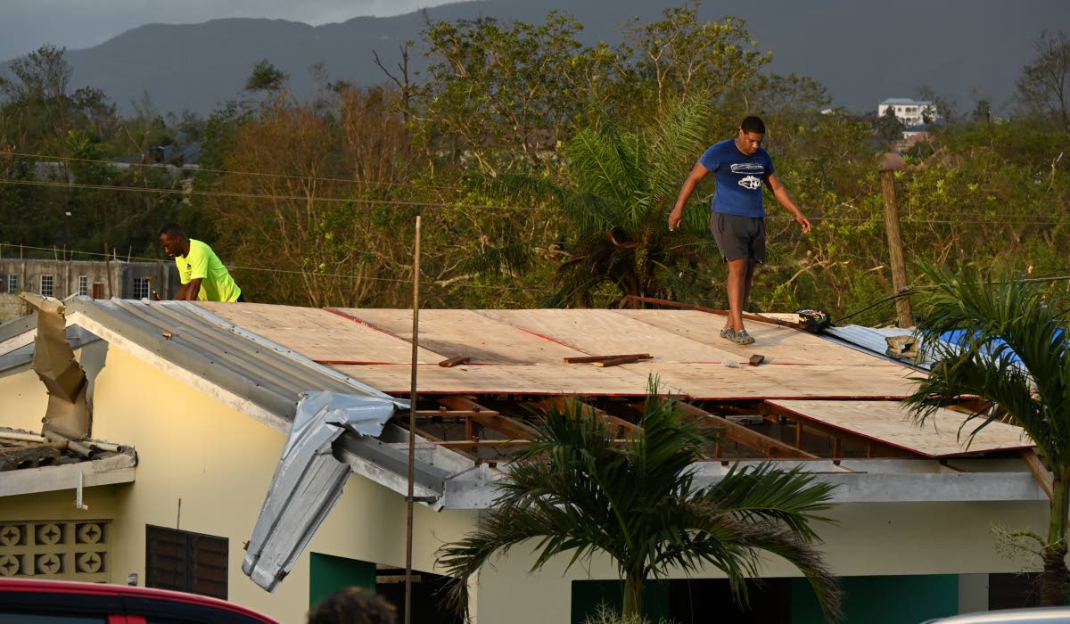 A man examines sections of one of the rooftops at St Elizabeth Technical High School destroyed by Hurricane Melissa.