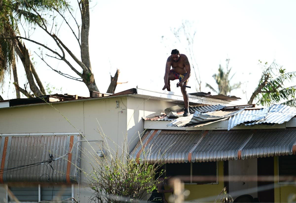 A homeowner in Black River, St Elizabeth, is seen repairing the roof of his house, which was destroyed by Hurricane Melissa last October.