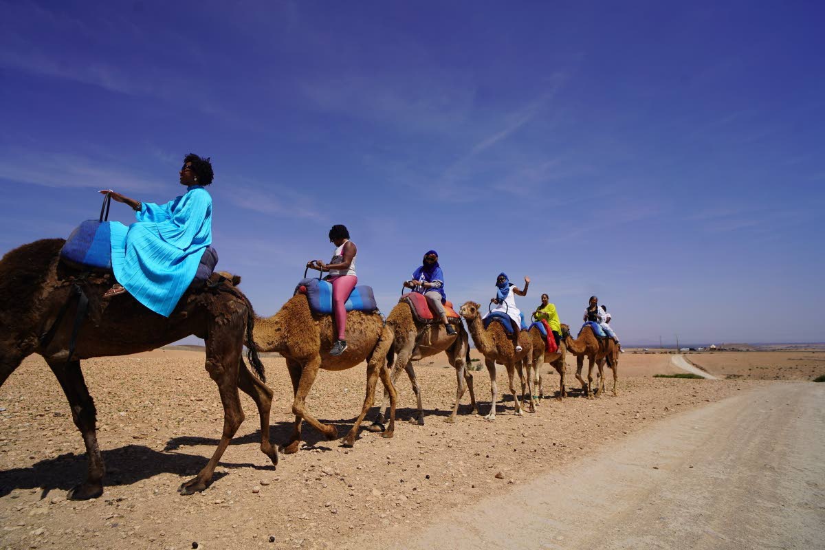 
In this photo provided by Micaela Sling Media, Roshida Dowe (foreground) rides a camel accompanied by several participants of the ExodUS Summit, an event business she co-leads to help Black women take career breaks and move abroad.