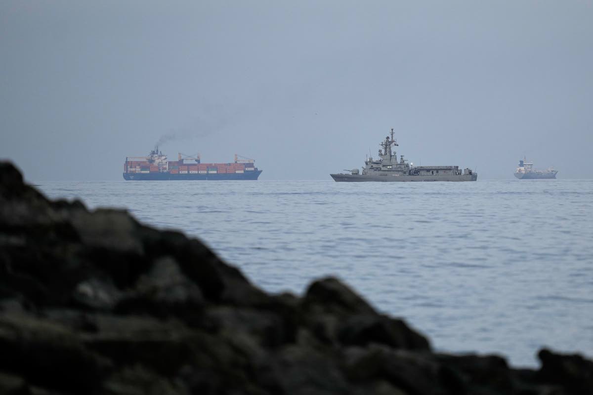 A UAE navy ship sails next to a cargo ship in the Strait of Hormuz as seen from Khor Fakkan, United Arab Emirates.