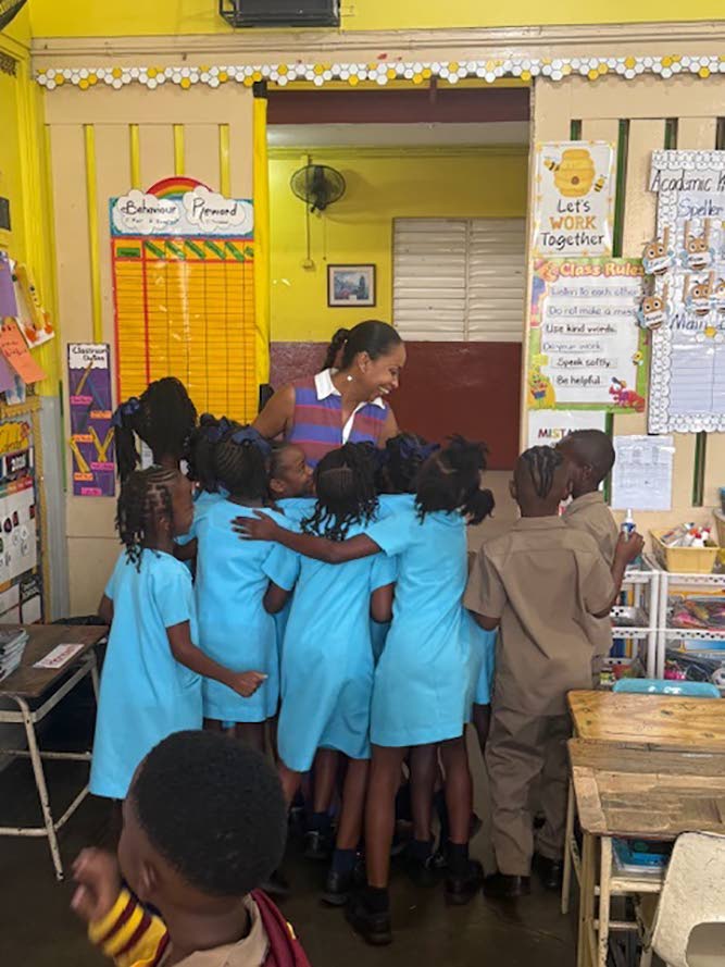 Talia Parkinson-Jones surrounded by students at Wolmer’s Preparatory School during a visit to her alma mater. 