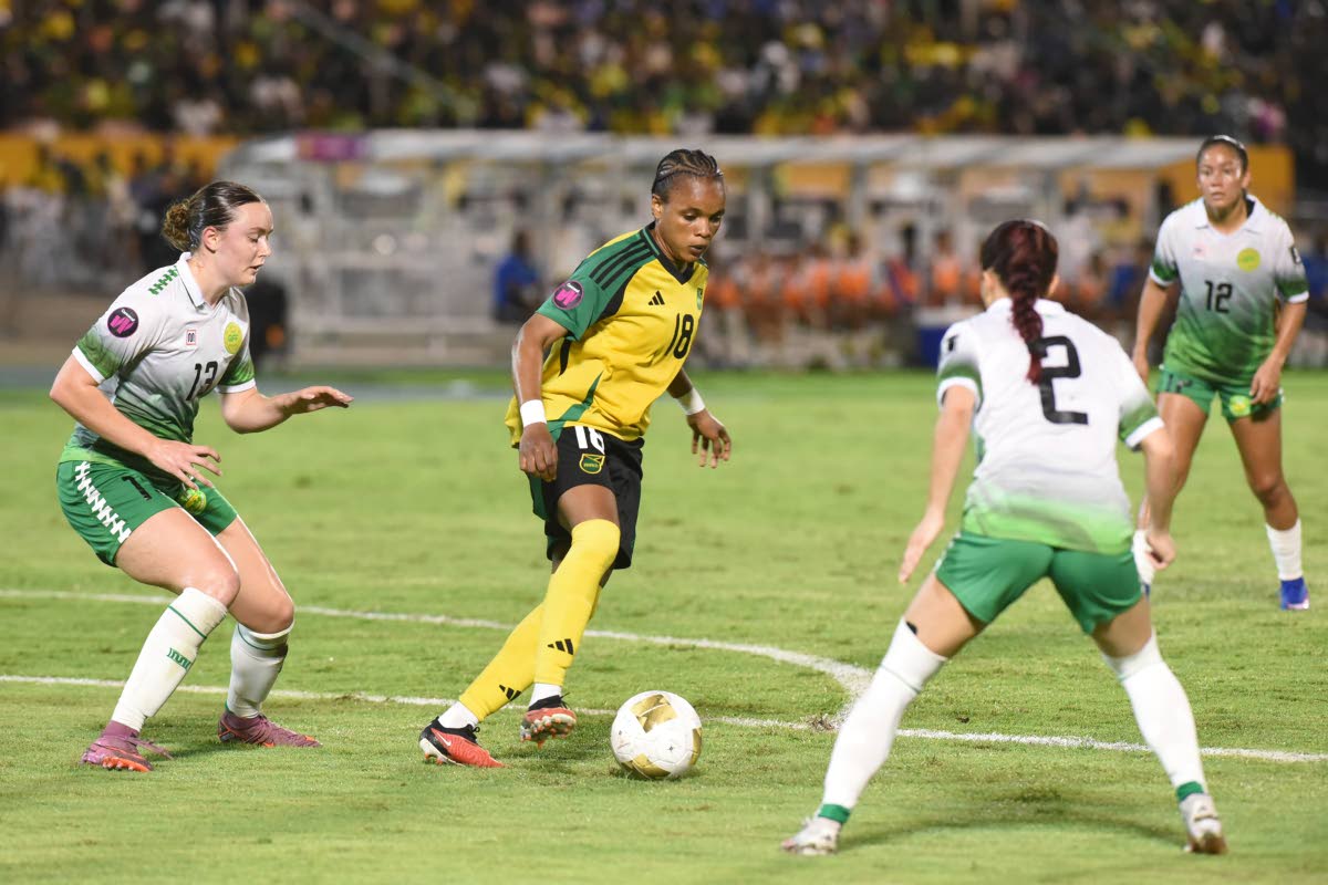 Reggae Girl Trudi Carter (centre) attempts to turn away from the attentions of Guyana's Heike Clarke (left) and Rylee Traicoff during their Concacaf W Qualifier inside the National Stadium on Saturday.