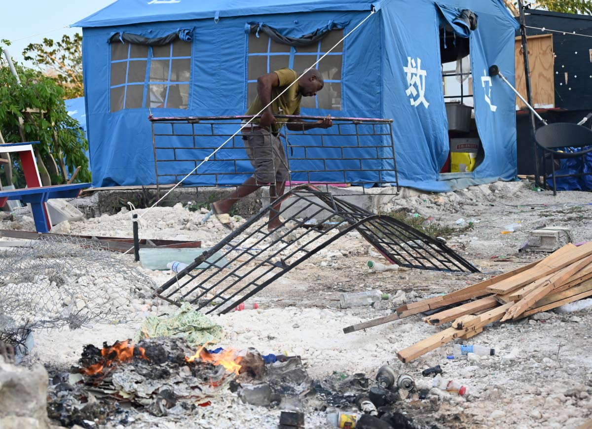 A man is seen removing items from the ground in Coopers Pen, Trelawny on August 20, after 20 houses had been demolished on August 14. Approximately 40 other households now fear that the demolition crew will return. 