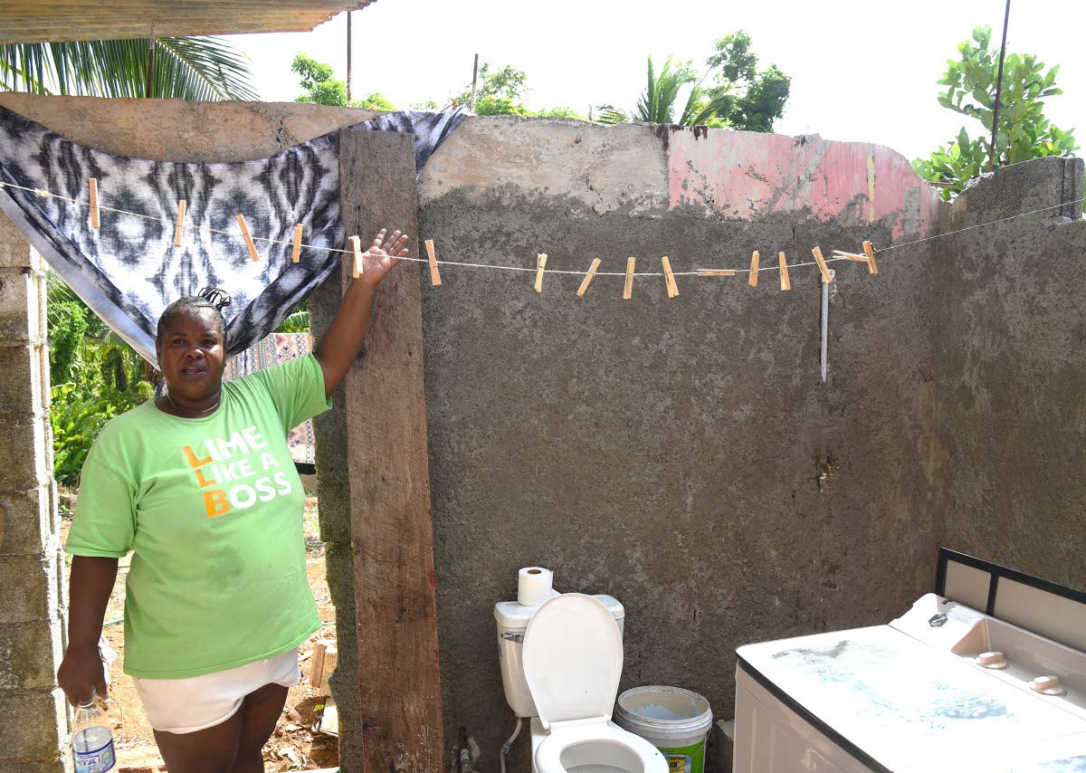 Shopkeeper Andrea Kelly shows her bathroom under construction. She has decided to prioritise this ahead of back-to-school expenses as she is tired of using neighbours’ bathrooms.