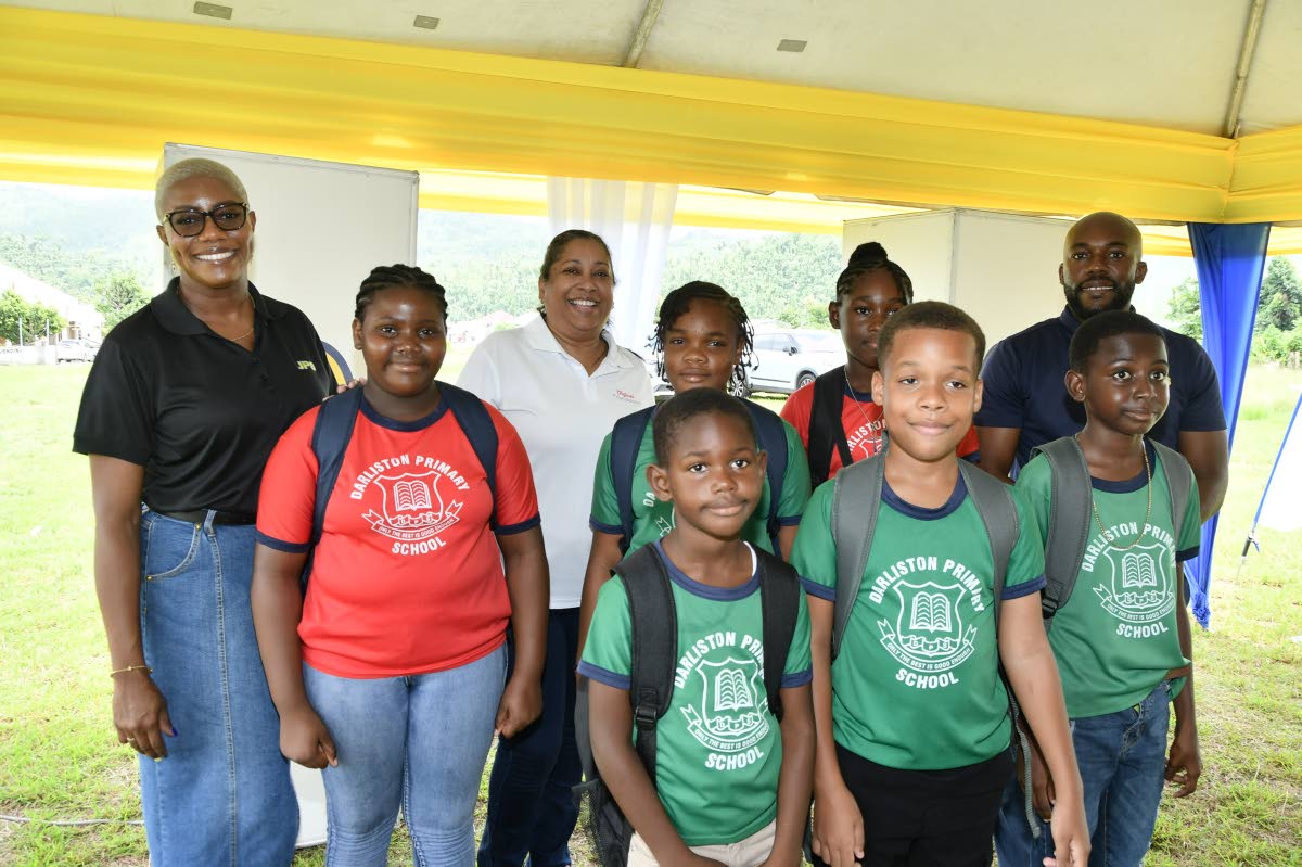 Pia Baker (back left), Digicel Foundation CEO, Charmaine Daniels (back centre) and Sameer Simms (back right) with some children from the Darliston Primary School, following the ribbon cutting for a new temporary office for the principal and the distributio