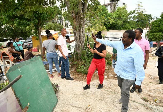 Minister without Portfolio in the Ministry of Economic Growth and Infrastructure Development with responsibility for Land Titling and Settlements, Robert Montague (right, foreground), greets residents while touring sections of the Coopers Pen community in 