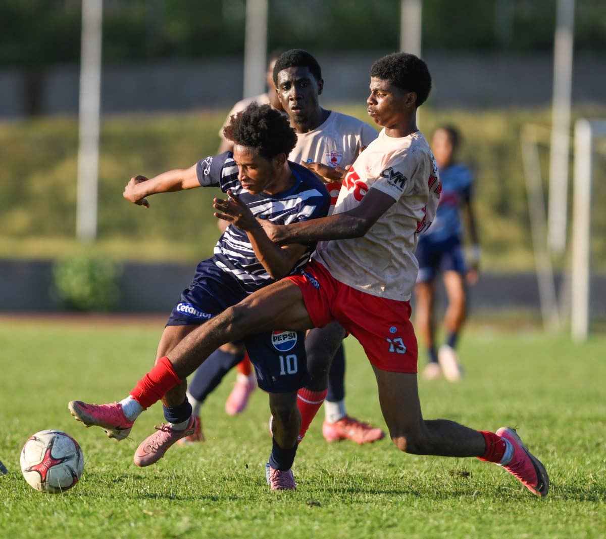 Sean Leighton of Mona High School (right) kicks the ball away from Jamone Lyle of Jamaica College (left) during the Walker Cup semi-final match on Saturday at Stadium East.