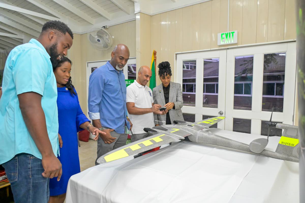 United Nations Development Programme (UNDP) Resident Representative in Jamaica, Dr Kishan Khoday (second right), demonstrates the operation of the Vertical Take-Off and Landing (VTOL) drone to Nationally Determined Contribution (NDC) Partnership In-Country