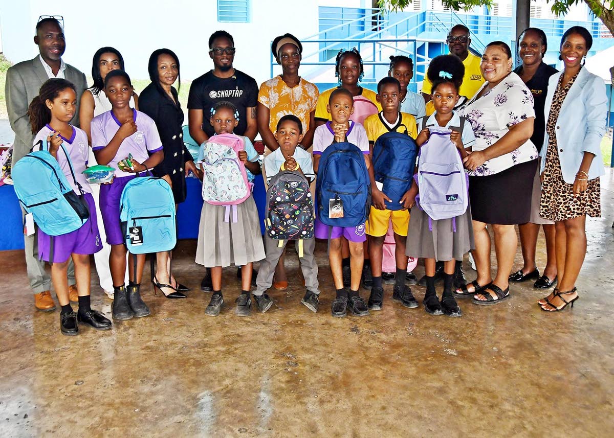 Students from Newstead Primary School in Cascade, St Mary, pose with Keron Erwin Morris (left), Cienna Smith (right), members of the Jamaica Real Estate Hub and sponsors, after receiving school bags and supplies.
