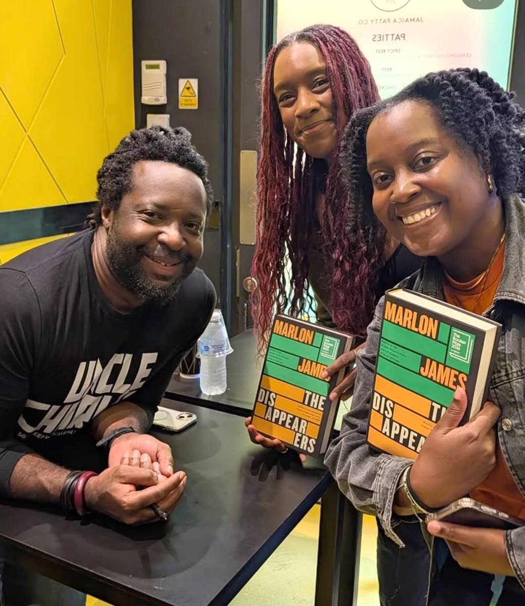 Two women get their photo with Marlon James after purchasing his book, The Disappearers, at the Jamaica Patty Company restaurant in Covent Garden.