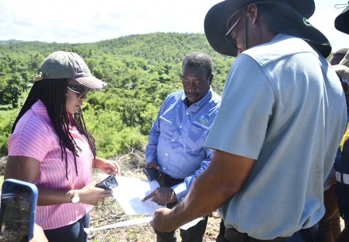Minister without Portfolio in the Ministry of Economic Growth and Infrastructure Development with responsibility for Land Titling and Settlements, Robert Montague (centre), examines plans for a new housing development in the Hague and Clifton area of Trela