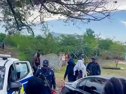 Police personnel escort the suspect in yesterday’s triple murder in Clarendon to a service vehicle. 