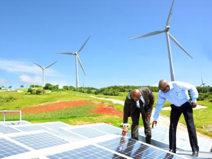In this November 2, 2016, then Energy Minister Dr Andrew Wheatley, (left) and then Chairman of Wigton Windfarm Duane Smith examine solar panels installed at the wind farm in Manchester.