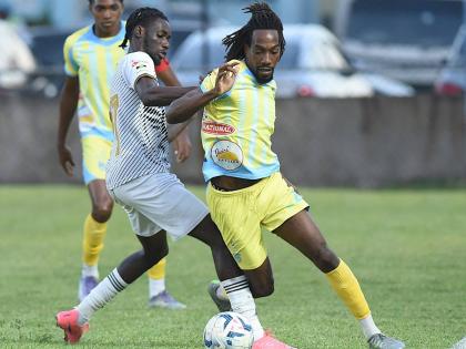 Jerome McLeary (centre) of Cavalier  challenges Waterhouse’s Omani Leacock during their Jamaica Premier League match at the Drewsland Mini Stadium yesterday. Home team Waterhouse won the game 2-1. 