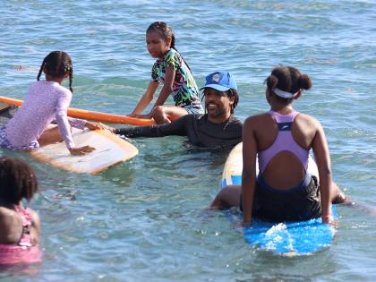 President of the Jamaica Surfing Association, Inilek Wilmot (second right), interacts with some of the children at the Next Wave JA surfing session in Bull Bay on Sunday. 