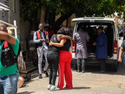 
Funeral home attendants put the bodies of seven-year-old Keriecia Hutchinson and her four-year-old brother, Samson Cameron, in their vehicle along Smith Lane in downtown Kingston yesterday after the two children died in a house fire. 